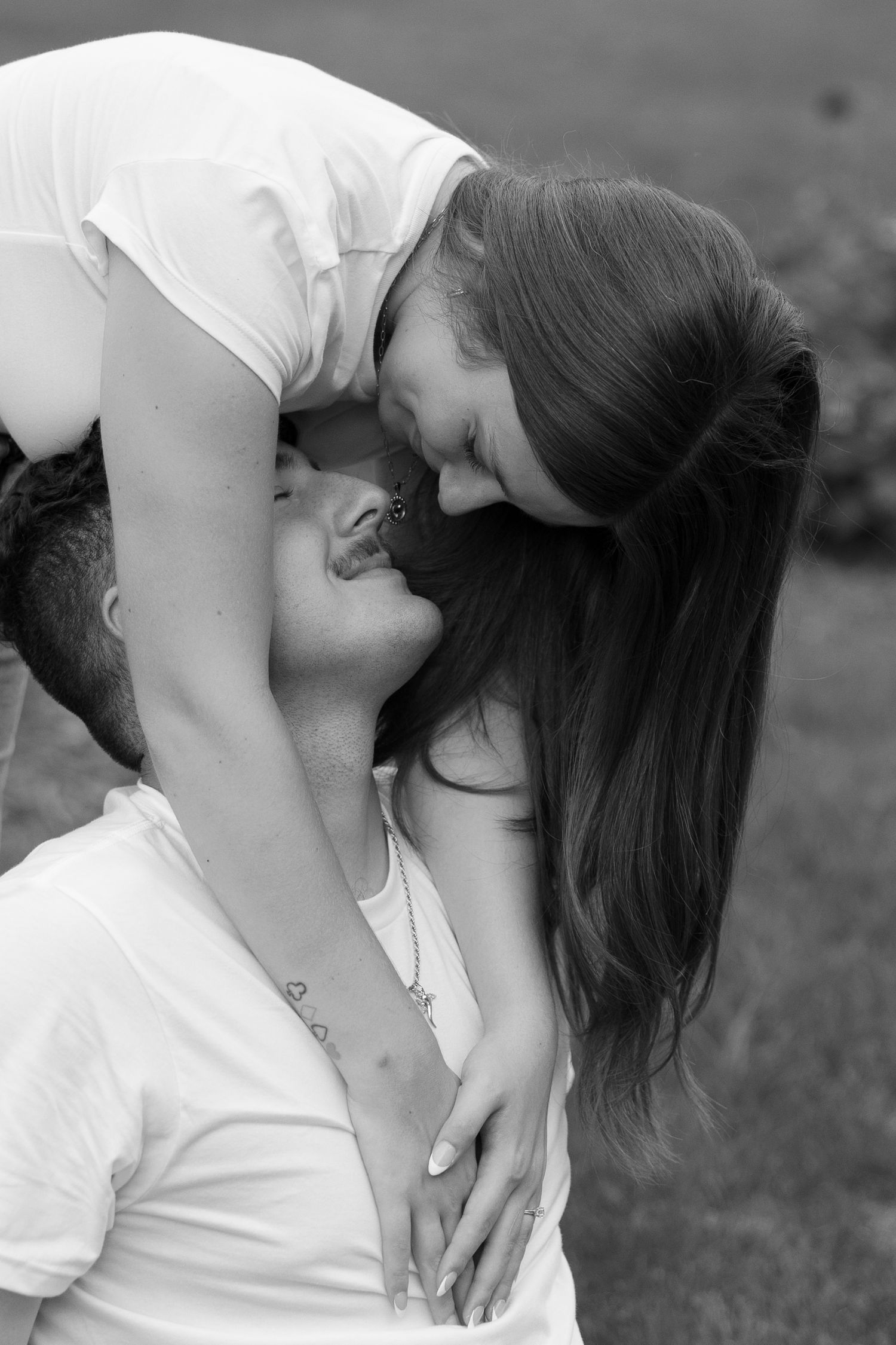 Black and white close-up of a couple sharing an intimate kiss outdoors.