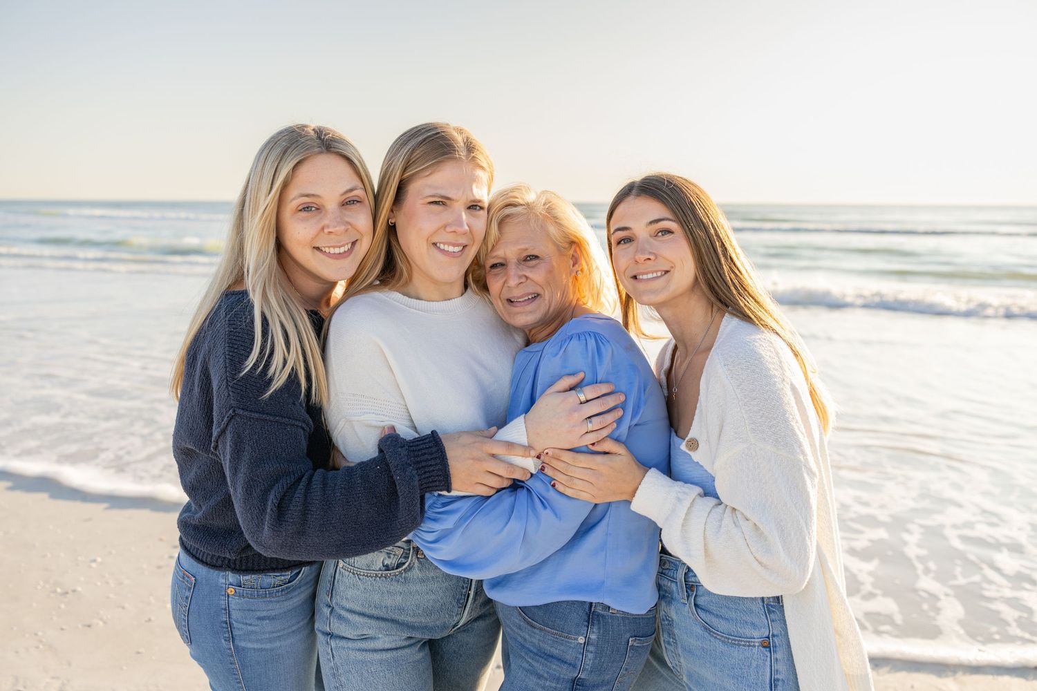 Family of four standing together on the beach during a sunset session.
