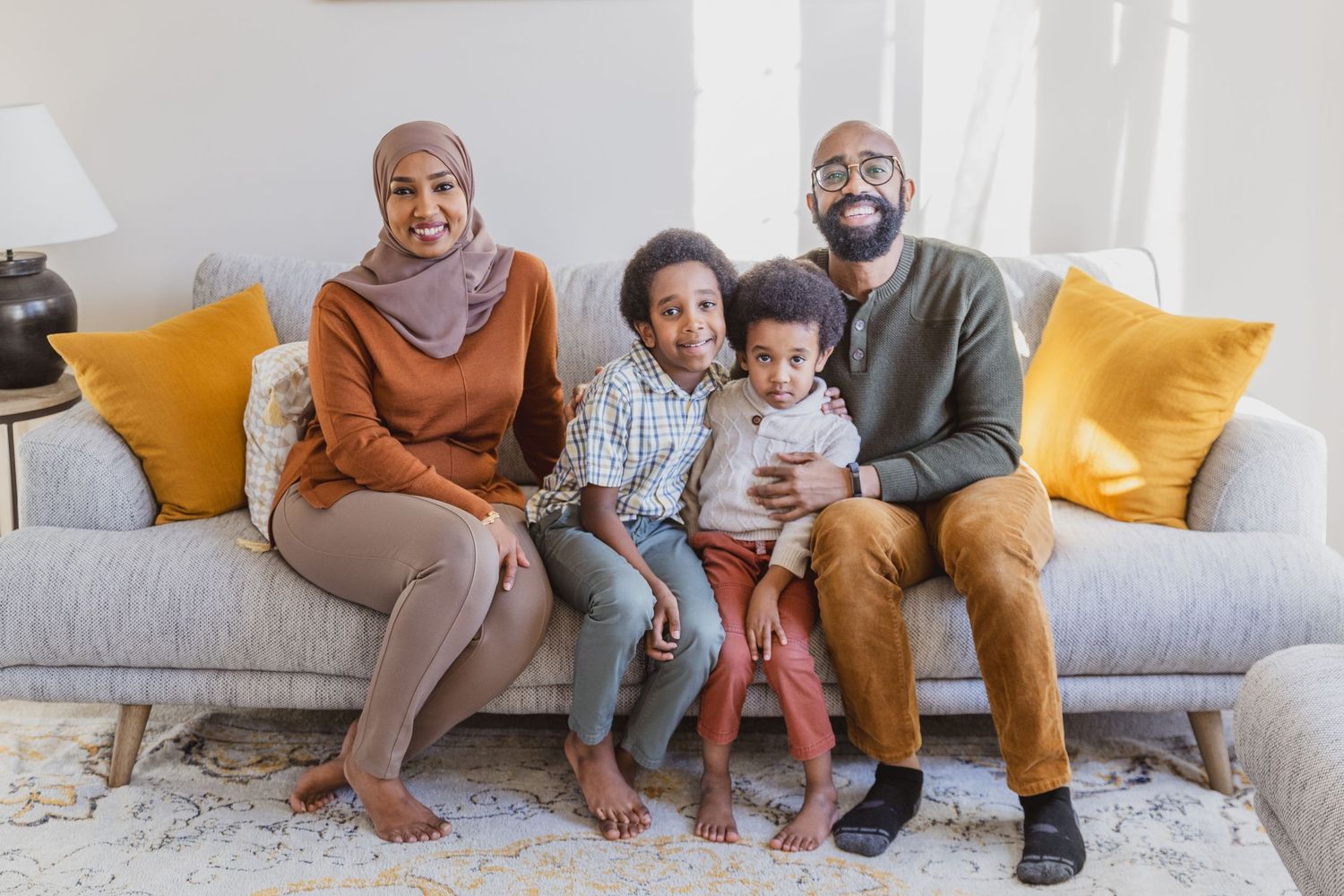 Mom, dad, and their two boys smiling in their beloved home in Savage, Minnesota during a fall family photography session
