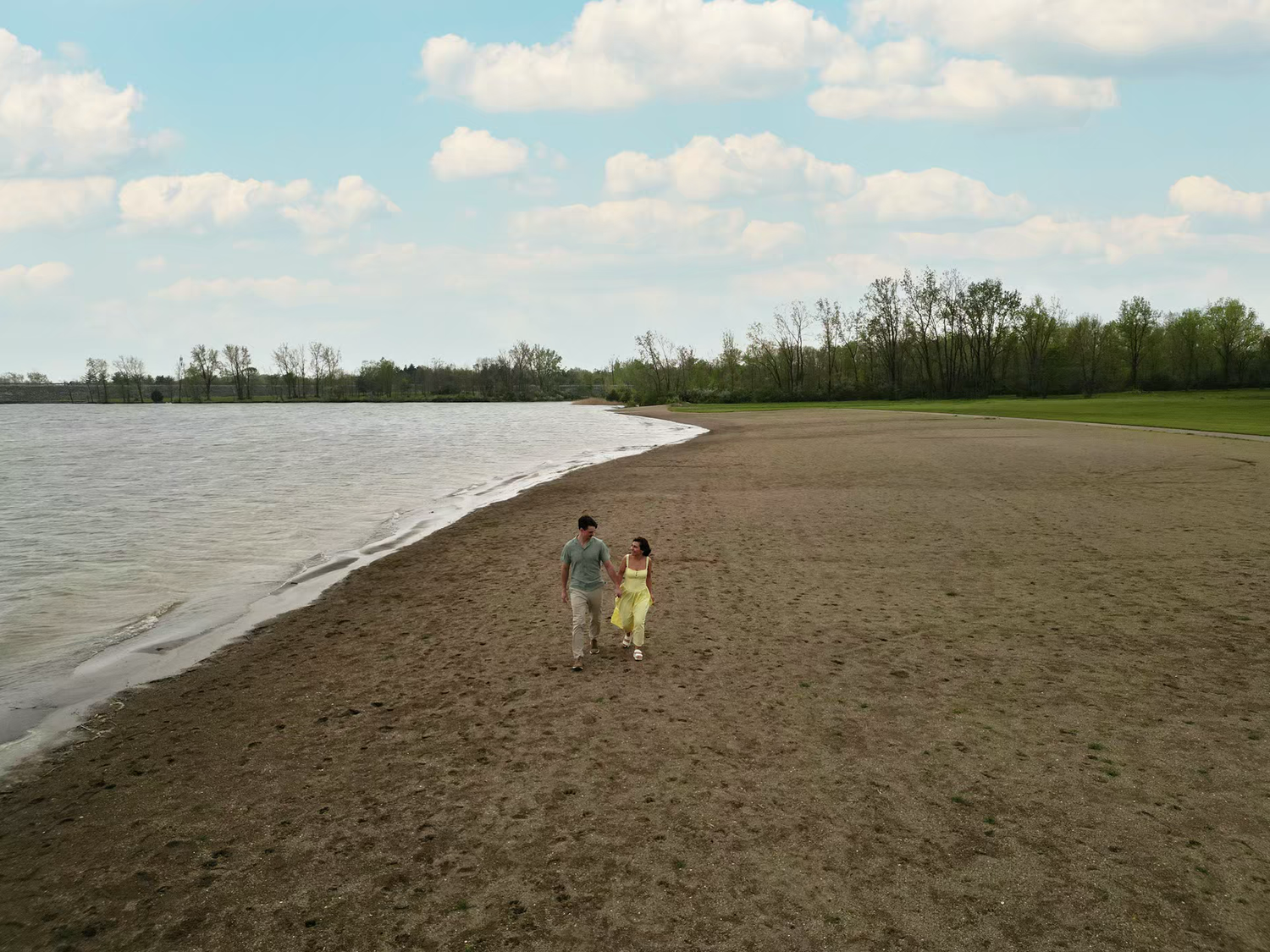 Couple walking hand in hand along a sandy beach shoreline at  ALUM CREEK BEACH for ENGAGEMENT photo