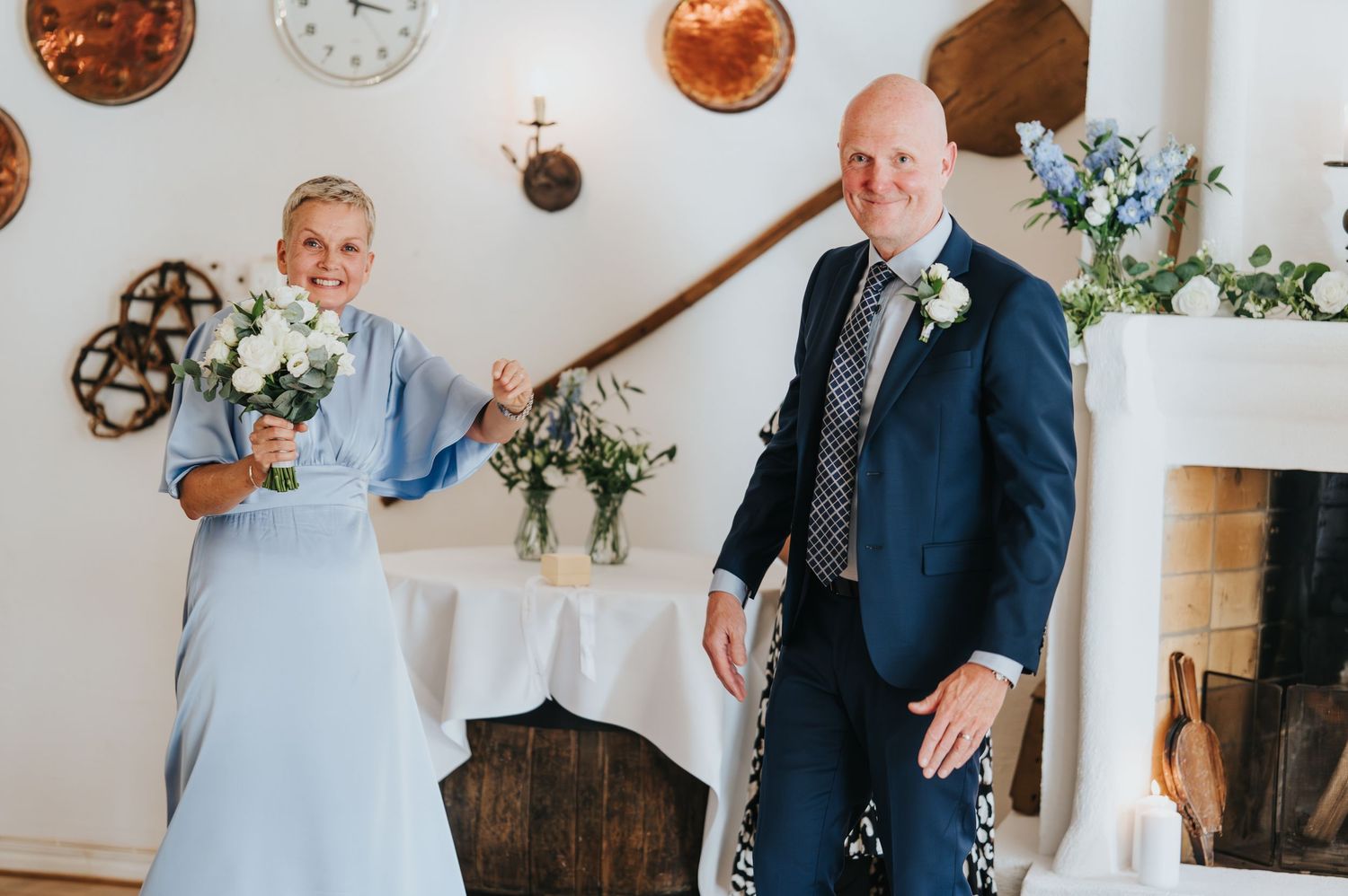 Bride and groom walking hand in hand down a cobblestone path between white buildings on their wedding day.