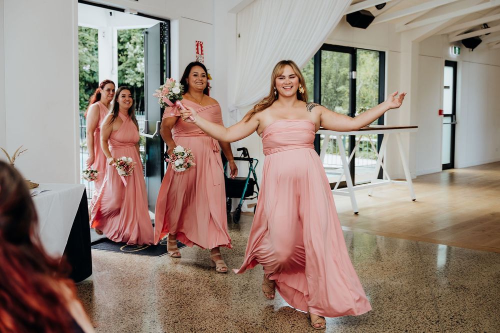 Bridesmaids in pink dresses dancing at a wedding reception.