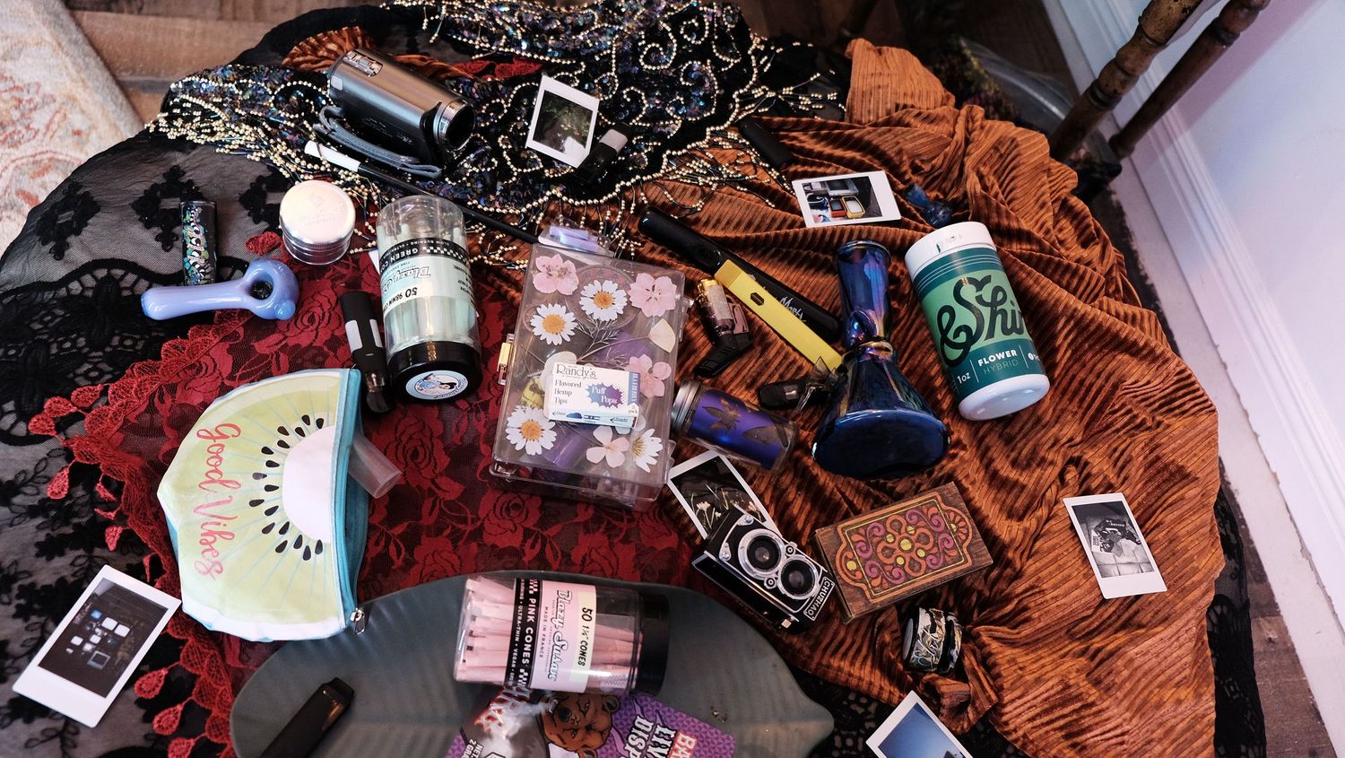 Flat lay of beauty products, accessories, and lifestyle items arranged on a colorful fabric surface.