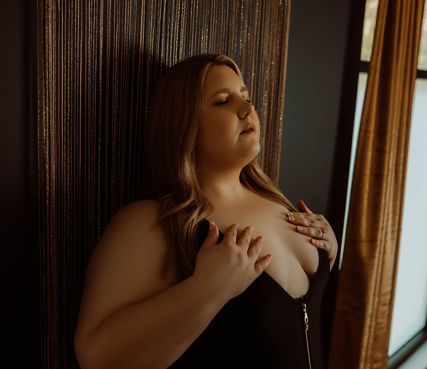 blonde woman in black lingerie leans against wall by Boudoir by KJ