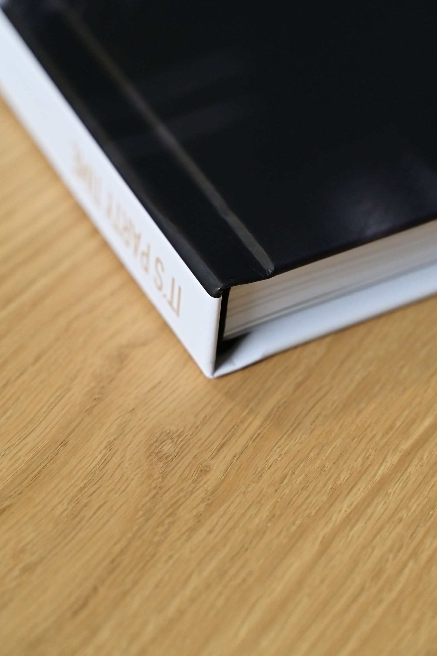 Close-up of a hardcover photo book spine on a wooden surface titled Its Party Time.