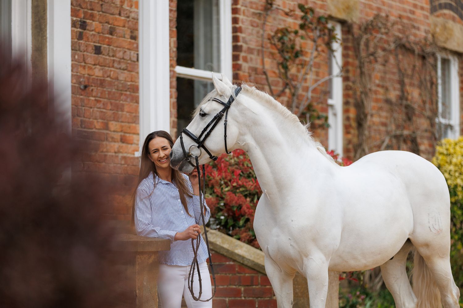 A horse and its rider enjoy an outdoor photoshoot session near rustic wooden fencing on a sunny day.
