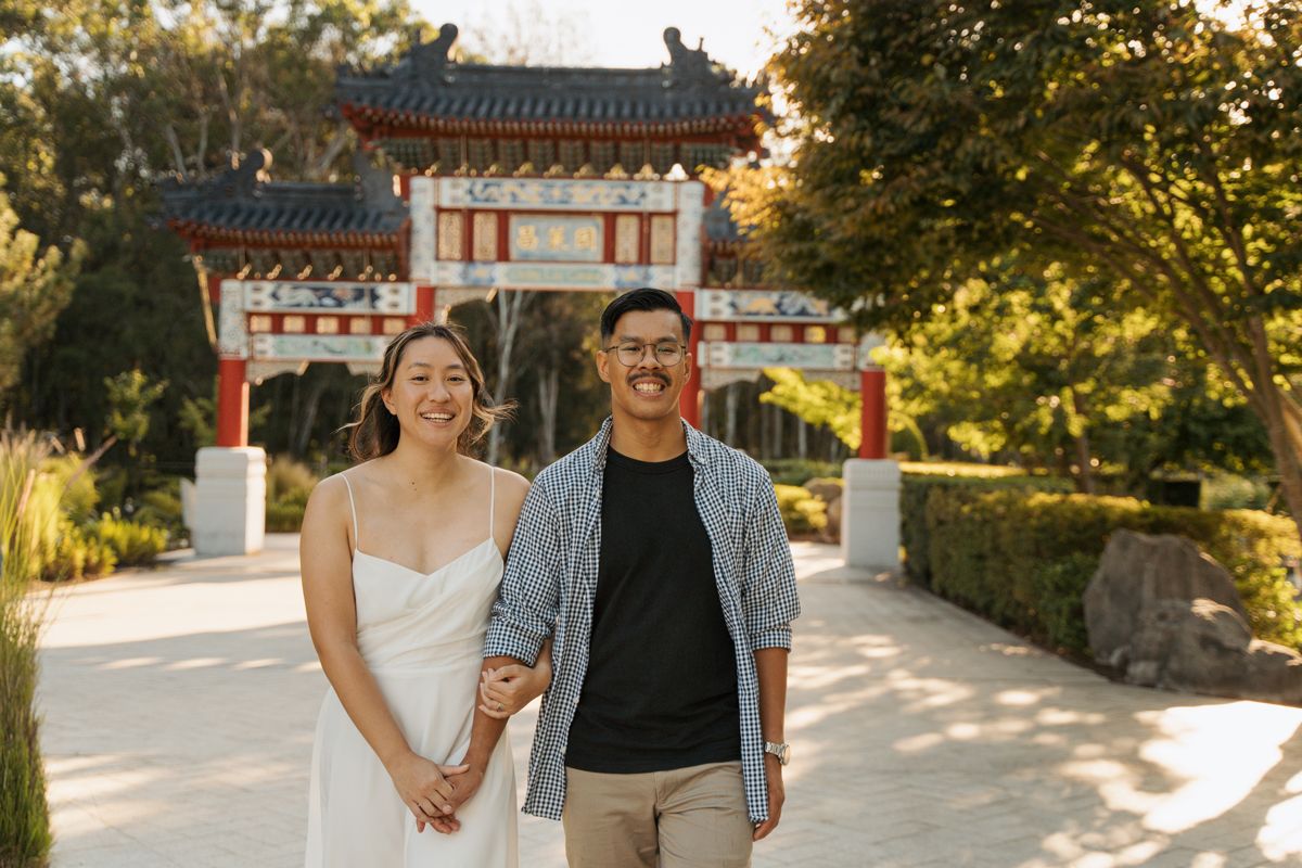 Couple smiling in front of a traditional Chinese gate at a scenic Nurragingy garden in western sydney couples photoshoot