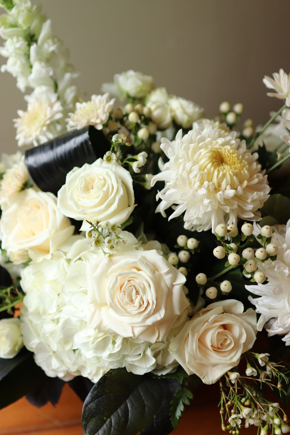 Elegant white roses and chrysanthemums arranged with delicate berries in floral display.