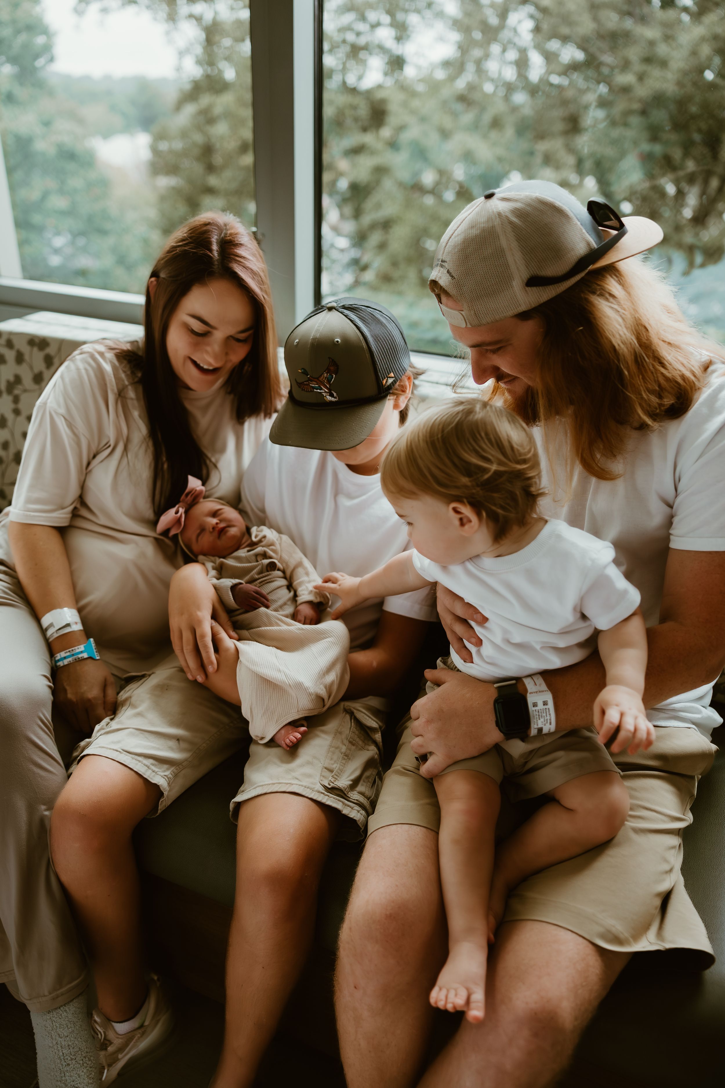 Loving family admiring their newborn baby girl as older sibling gently touches her hand.
