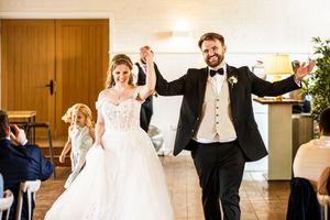 Smiling bride and groom making a grand entrance holding hands at their wedding reception.