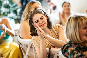 Emotional wedding guest clasping hands to face with joyful expression during reception.