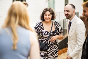 Wedding guests laughing and socializing in stylish outfits at outdoor wedding reception.