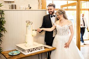 Newlyweds cutting elegant white wedding cake together at their wedding reception.