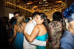 Two women sharing a warm embrace on the wedding reception dance floor.
