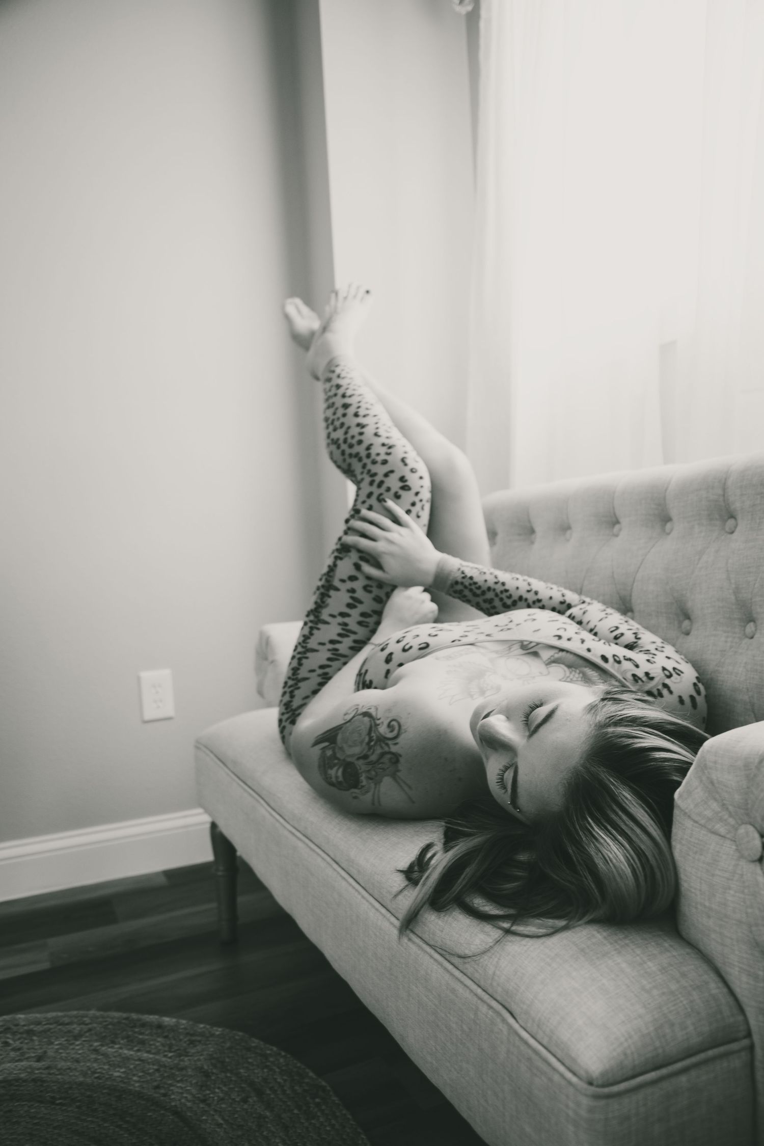 A person lies on a gray couch in a series of black and white photographs showing different reclining positions.