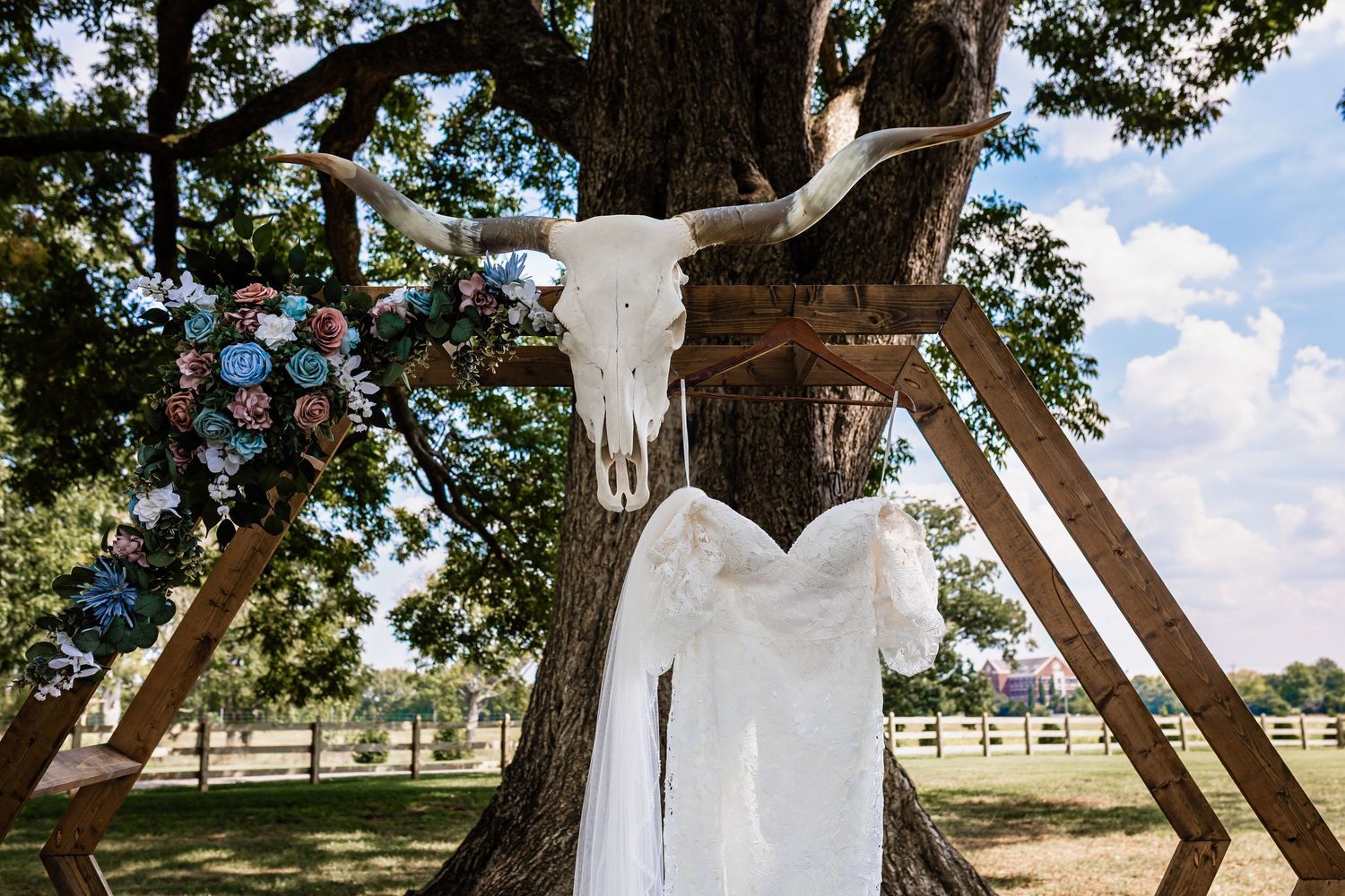 a wedding dress hanging from a wedding arbor in the grove ceremony location at Williamson Family Farm in Murfreesboro, Tennessee