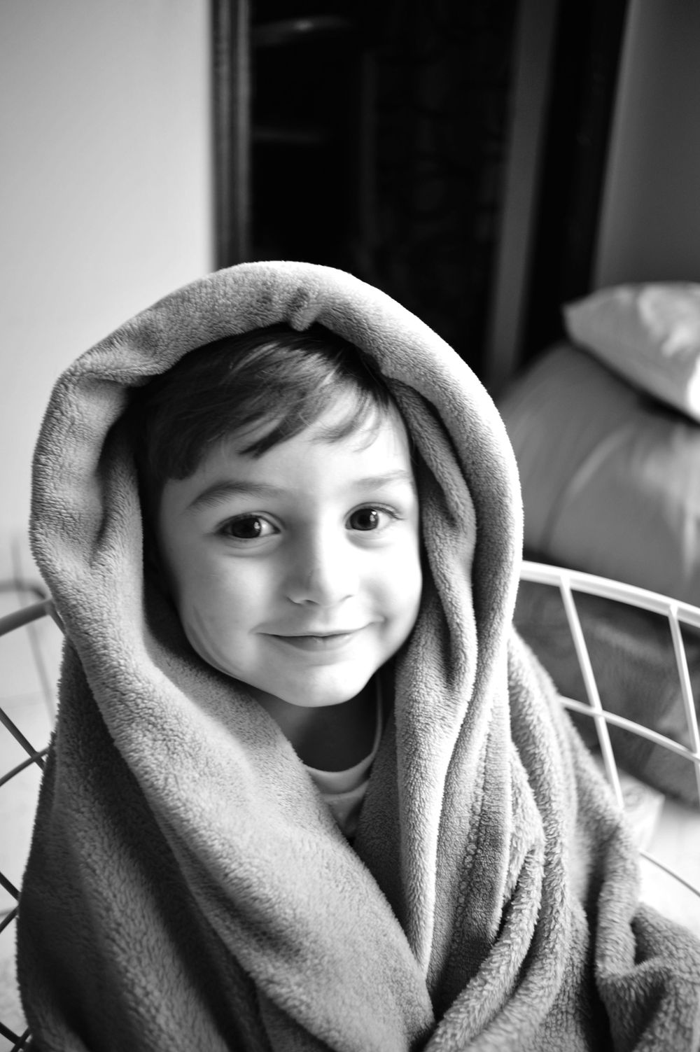 Black and white portrait series showing a child wrapped in a soft blanket with changing expressions.