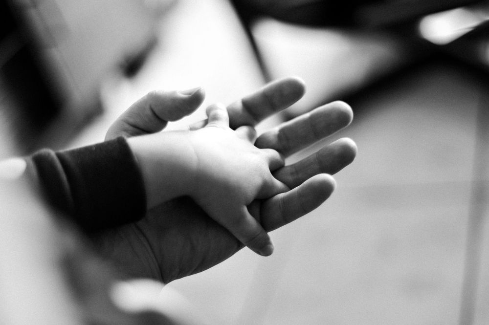 A black and white close-up photo shows hands holding a piece of chalk against a blurred background.