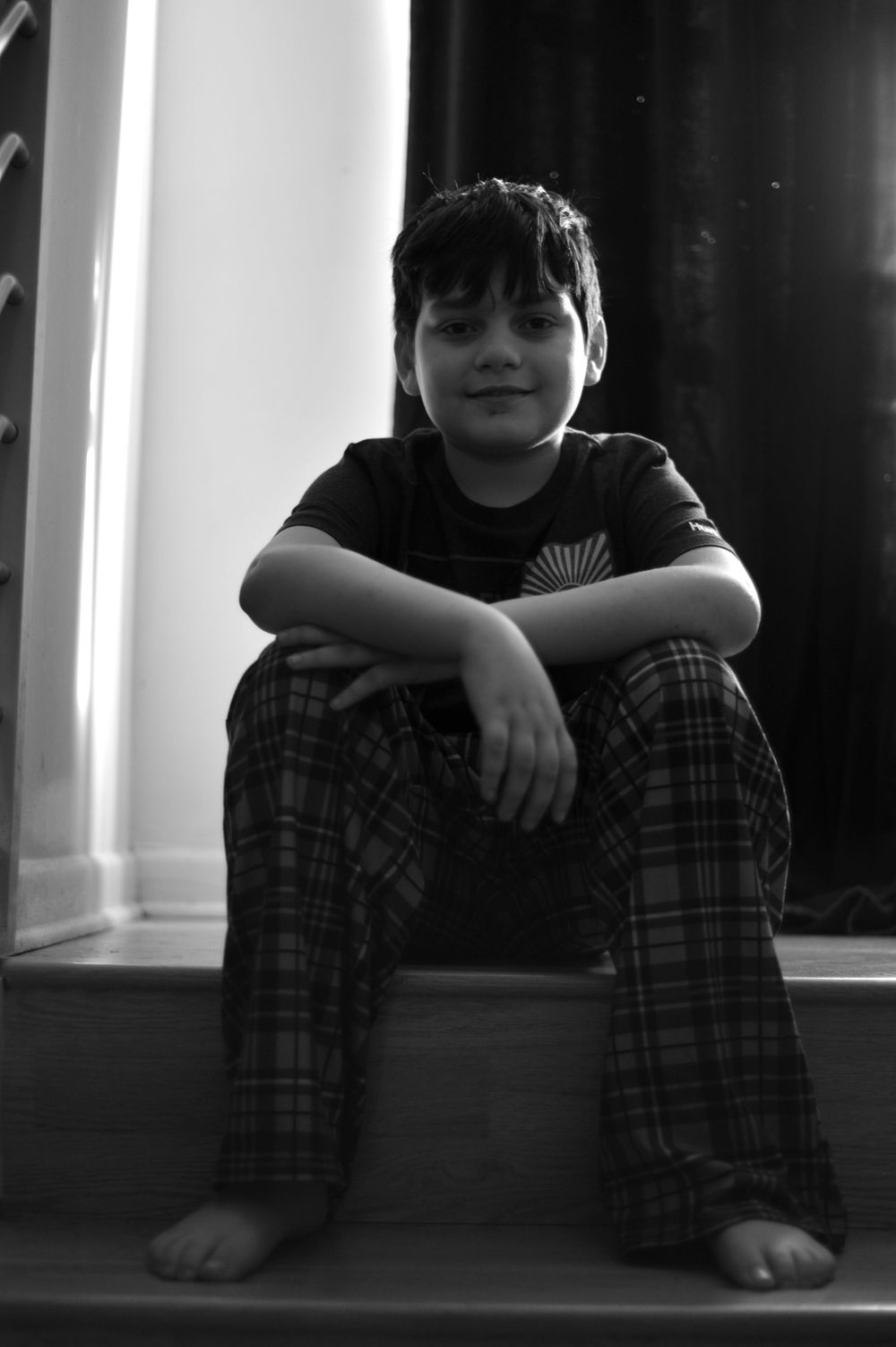 A black and white photo series shows someone sitting on the floor in plaid pajama pants against a bright window.
