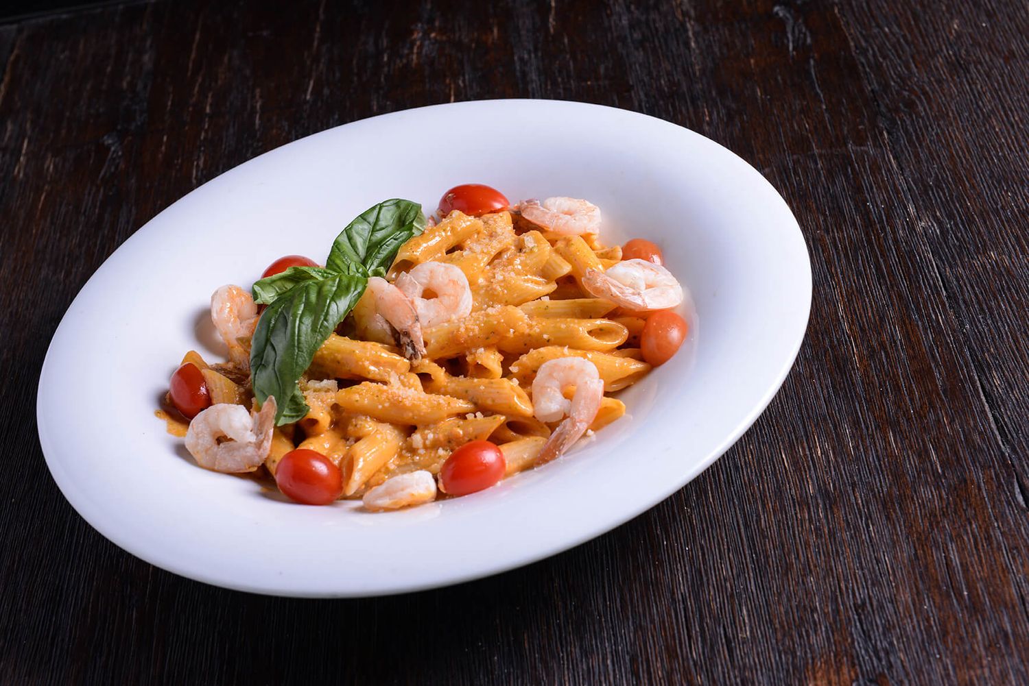 Pasta dishes with shrimp and fresh herbs served on white plates.