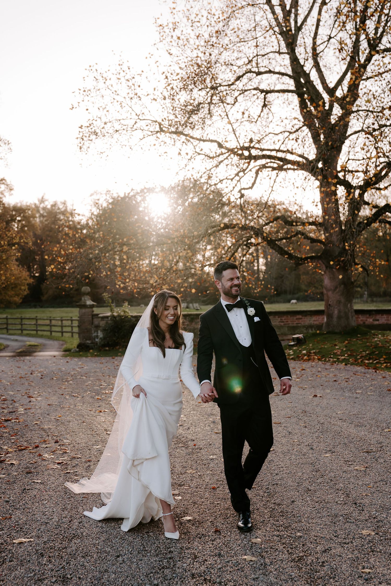 bride and groom walking towards Iscoyd park holding hands as the sun sets