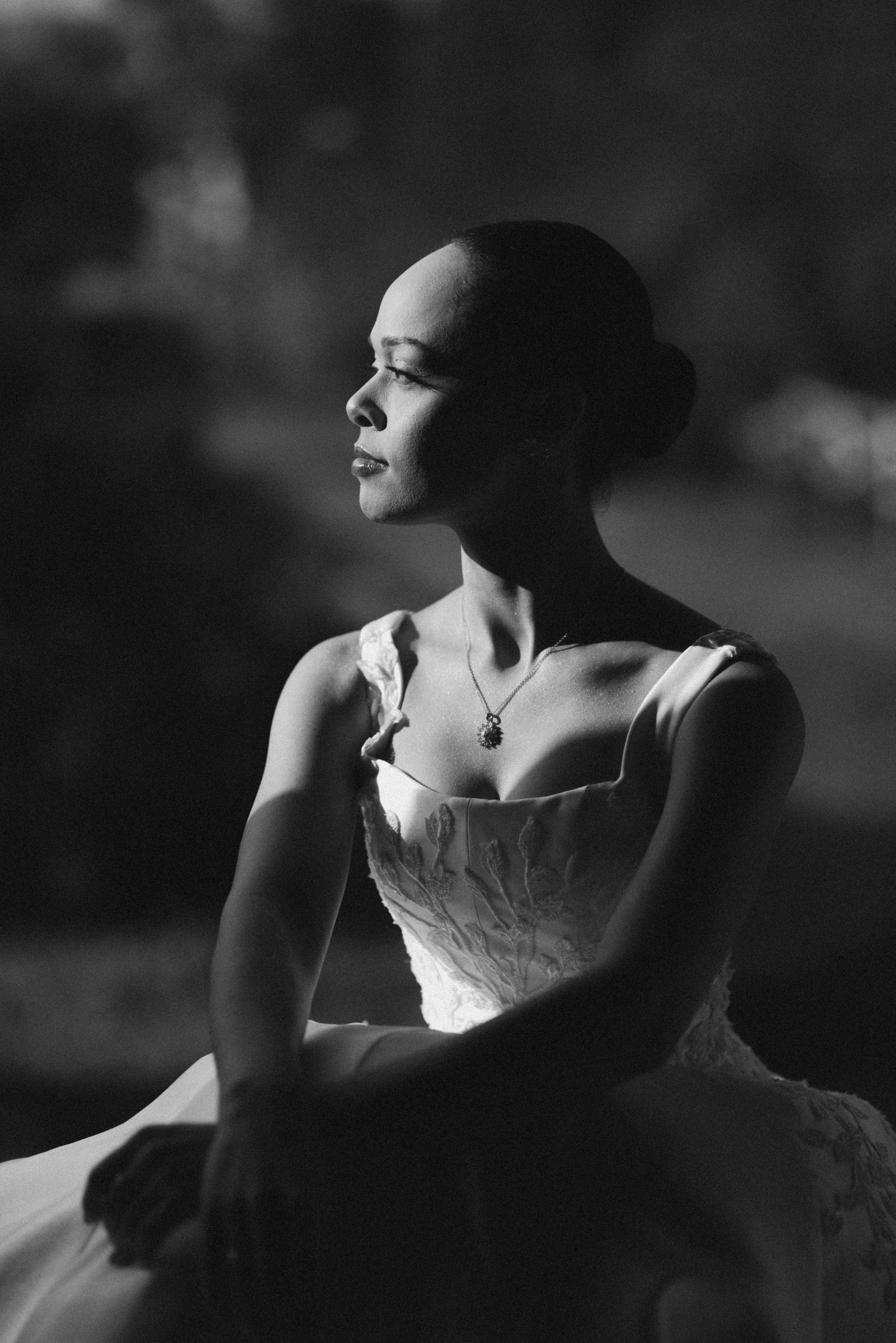 Elegant black and white portrait of a dancer in a white tulle dress looking to the side with graceful poise.