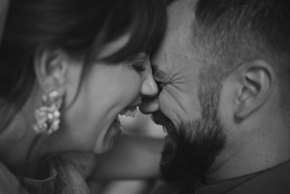 A romantic black and white close-up photo of a couple sharing a tender moment with their noses touching.
