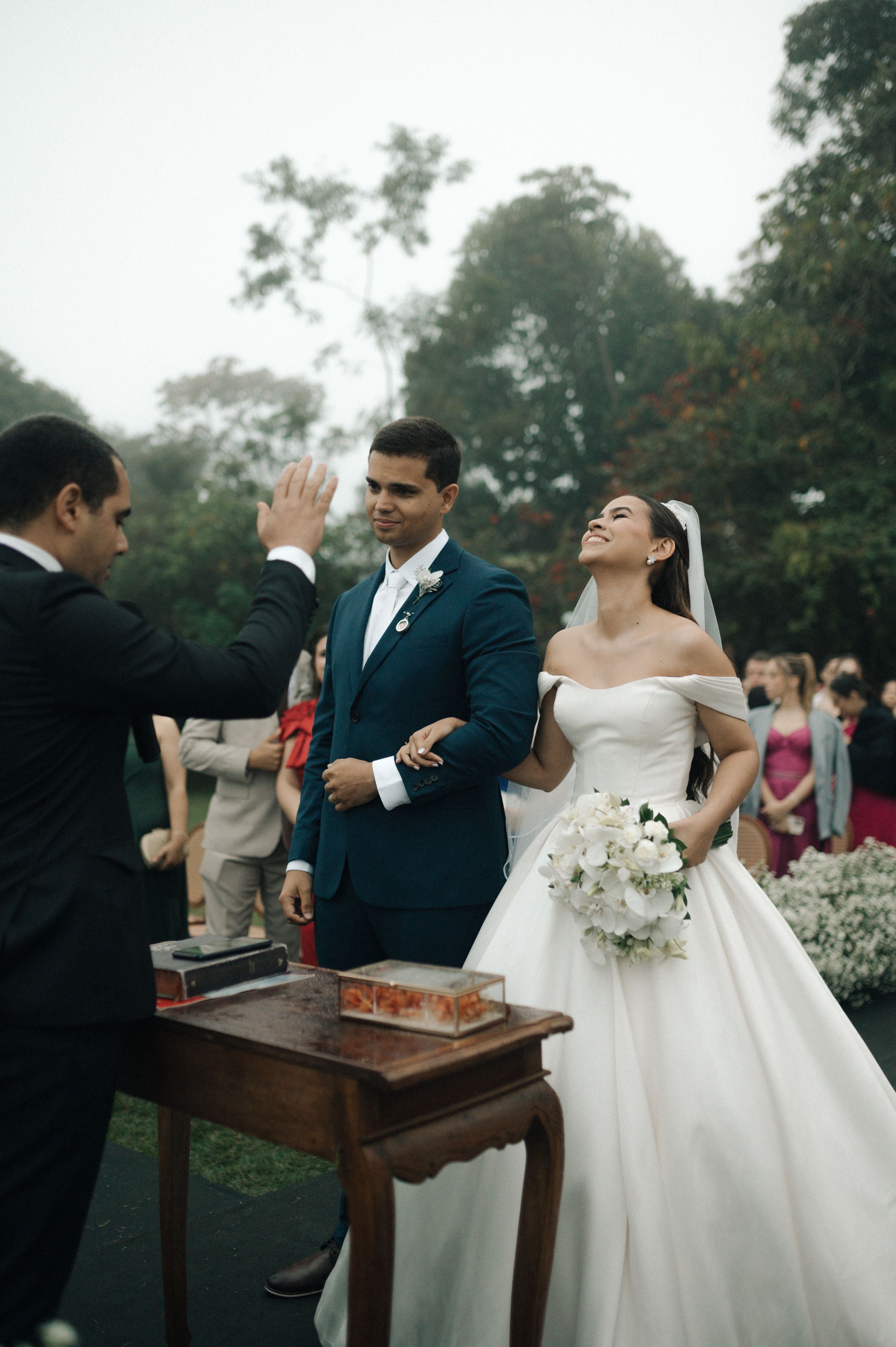 A couple and guests participate in a traditional wedding ceremony ritual with a wooden box outdoors.