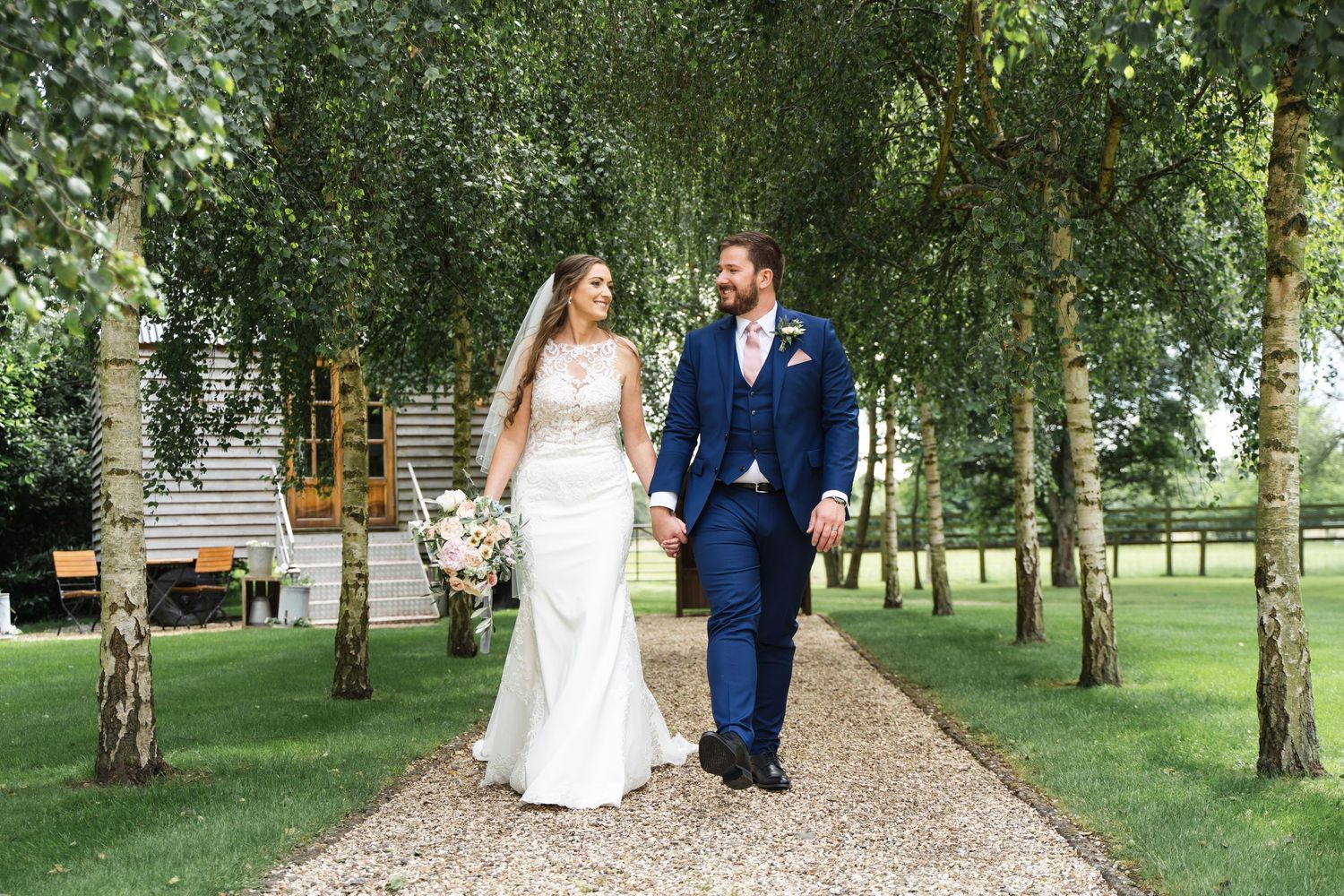Tythe Barn Bicester Wedding Photography with Bride & Groom walking whilst holding hands summer wedding
