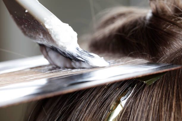 Macro close-up shot of scissors cutting through dark hair strands showing precise trimming technique.