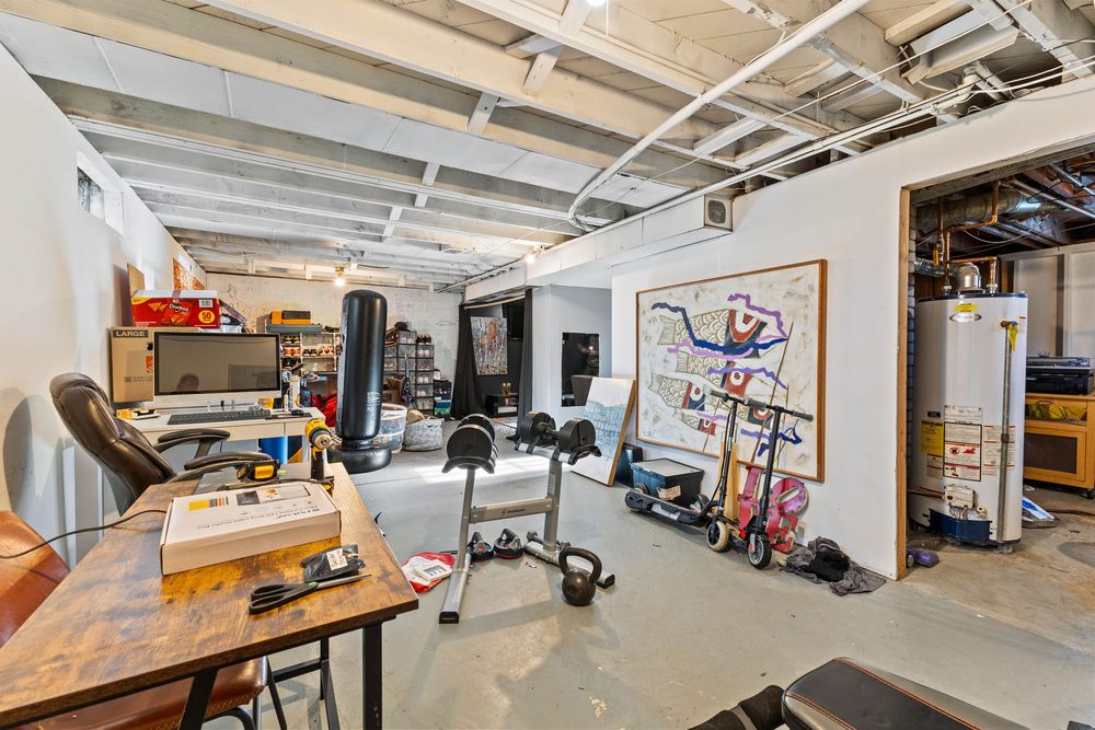Finished basement home gym with exercise equipment, open ceiling, and adjacent utility storage room.