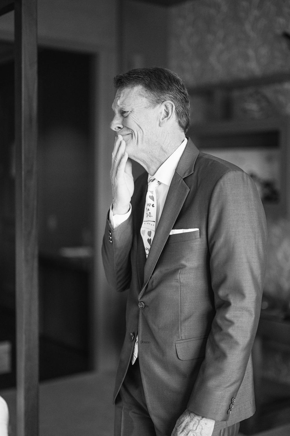 Black and white photo sequence of a groom in a grey suit having an emotional reaction.