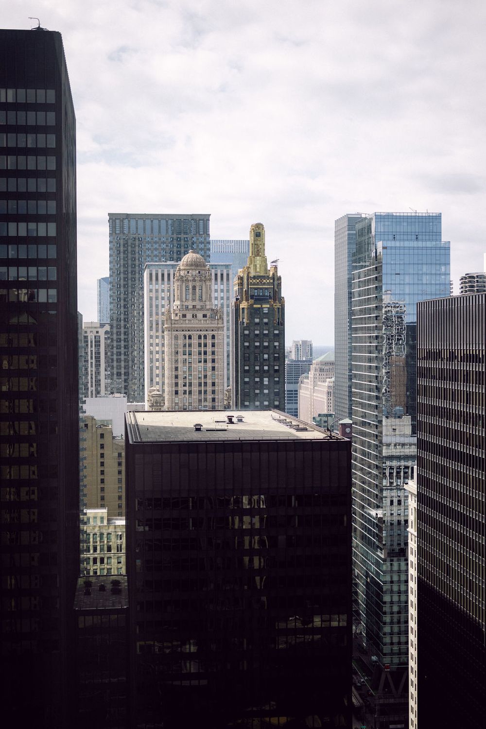 Urban skyline view of modern skyscrapers and office buildings in downtown Chicago against a cloudy sky.