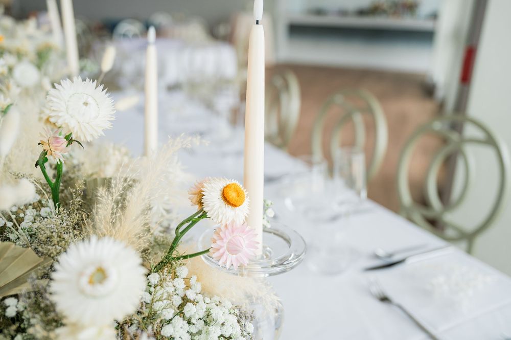 White floral arrangements with delicate blooms decorate round tables at an elegant event space.