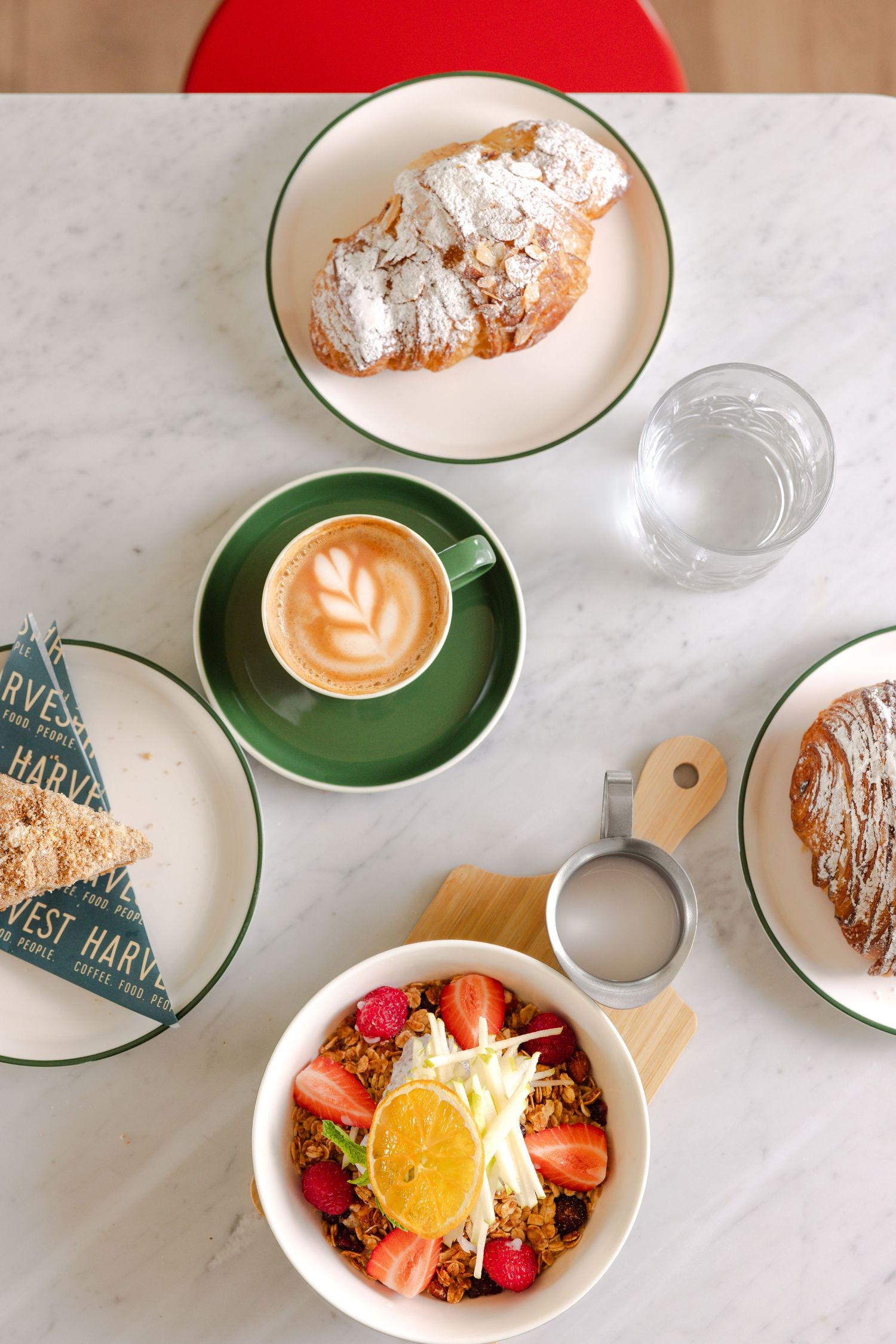 Breakfast spread: almond croissant, cappuccino, muesli bowl. Harvest, Midway