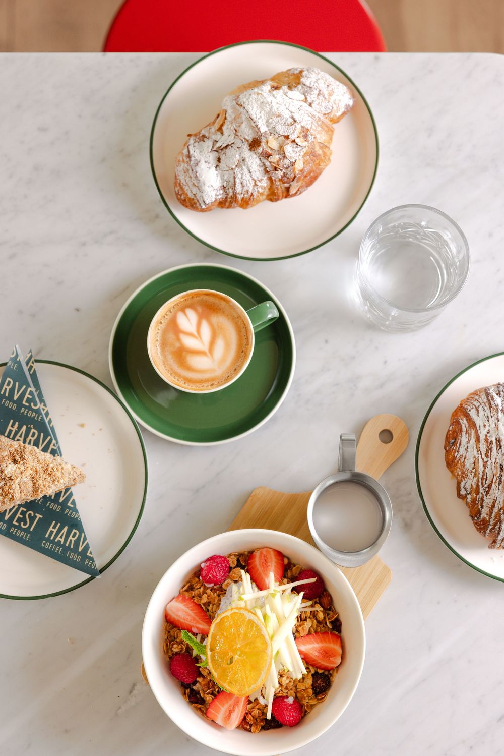Breakfast spread: almond croissant, cappuccino, muesli bowl. Harvest, Midway