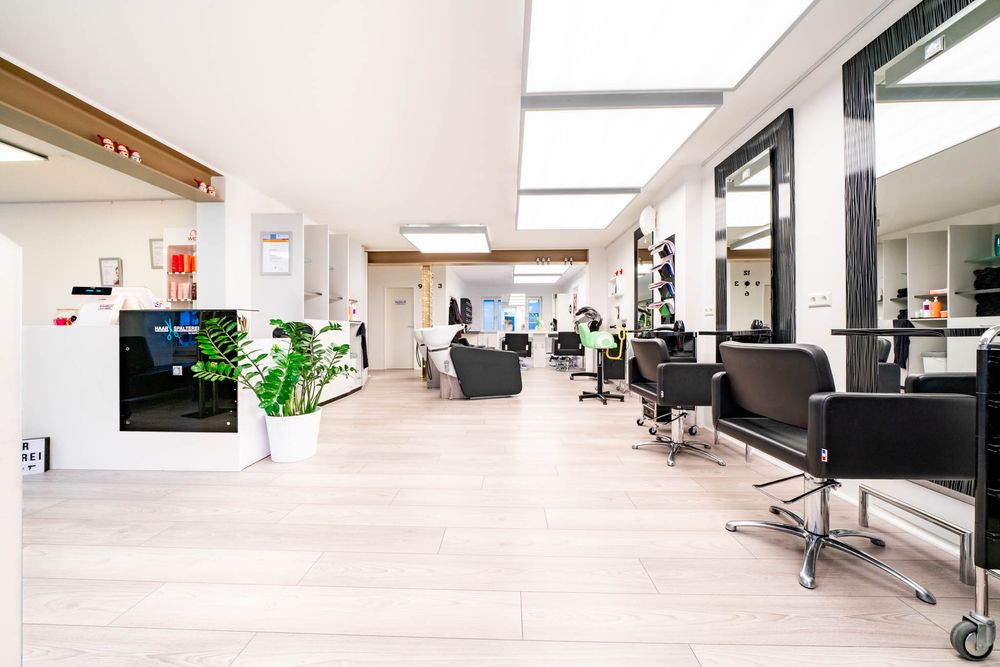 Modern open office space with white desks, black chairs, and natural lighting from large windows.