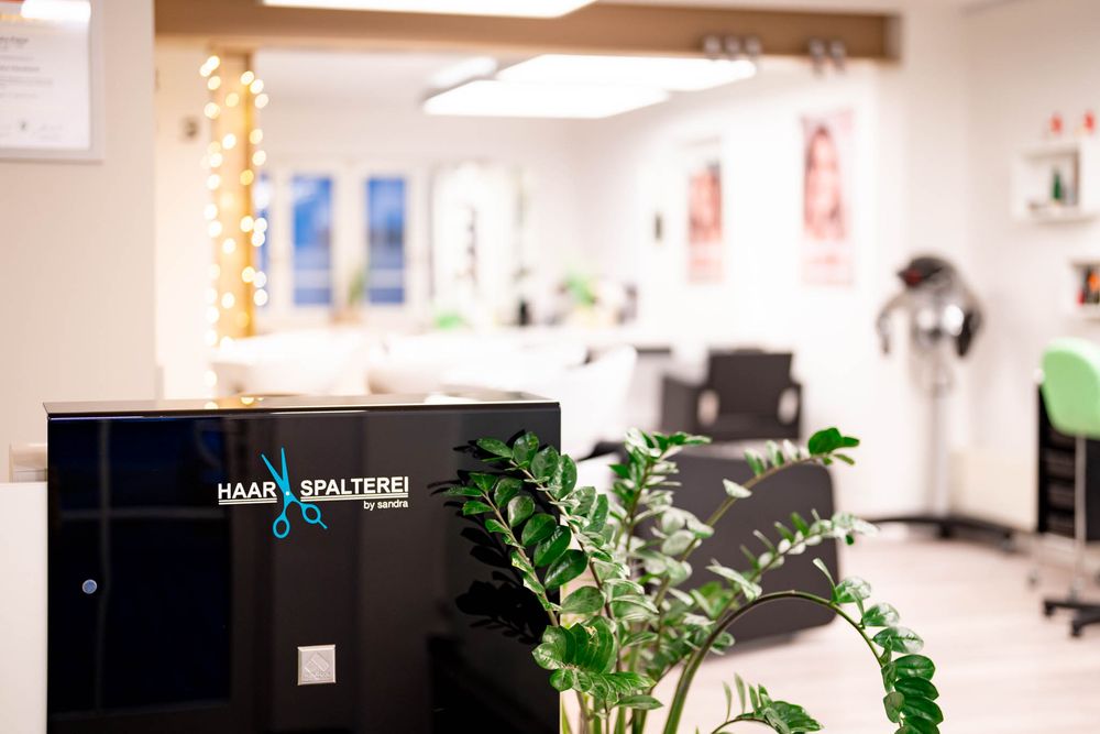 Modern office interior with white walls, fluorescent lighting, and potted plants along a hallway.