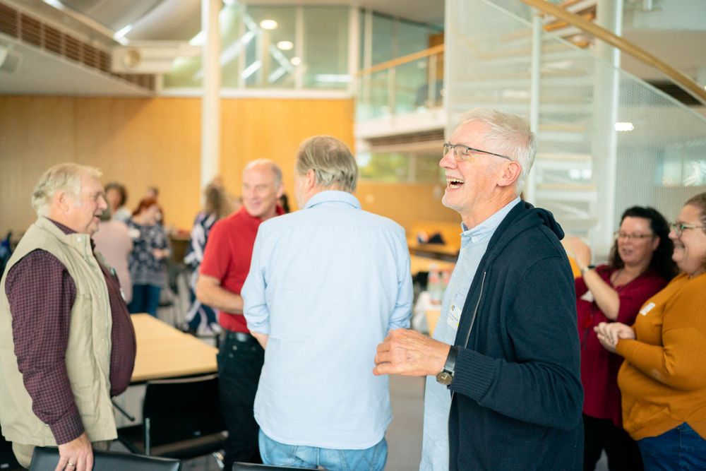 People dancing together in pairs at a social gathering in a brightly lit indoor venue.