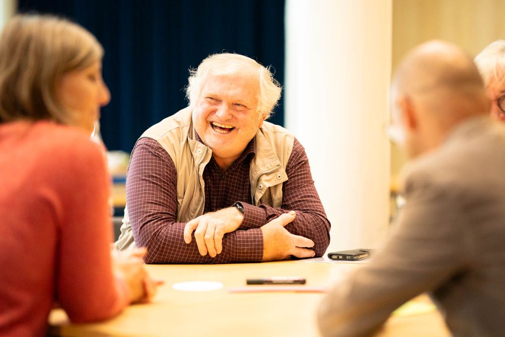 People gathered around a table share a joyful moment during a meeting or social gathering.