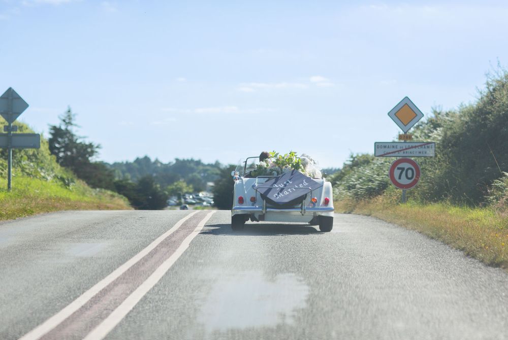 Couple drive through French countryside in open top sports car