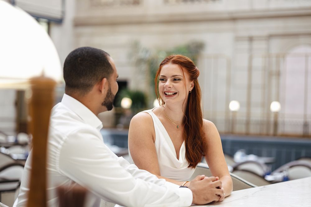 A couple shares an intimate moment at a dining table in a romantic restaurant setting.