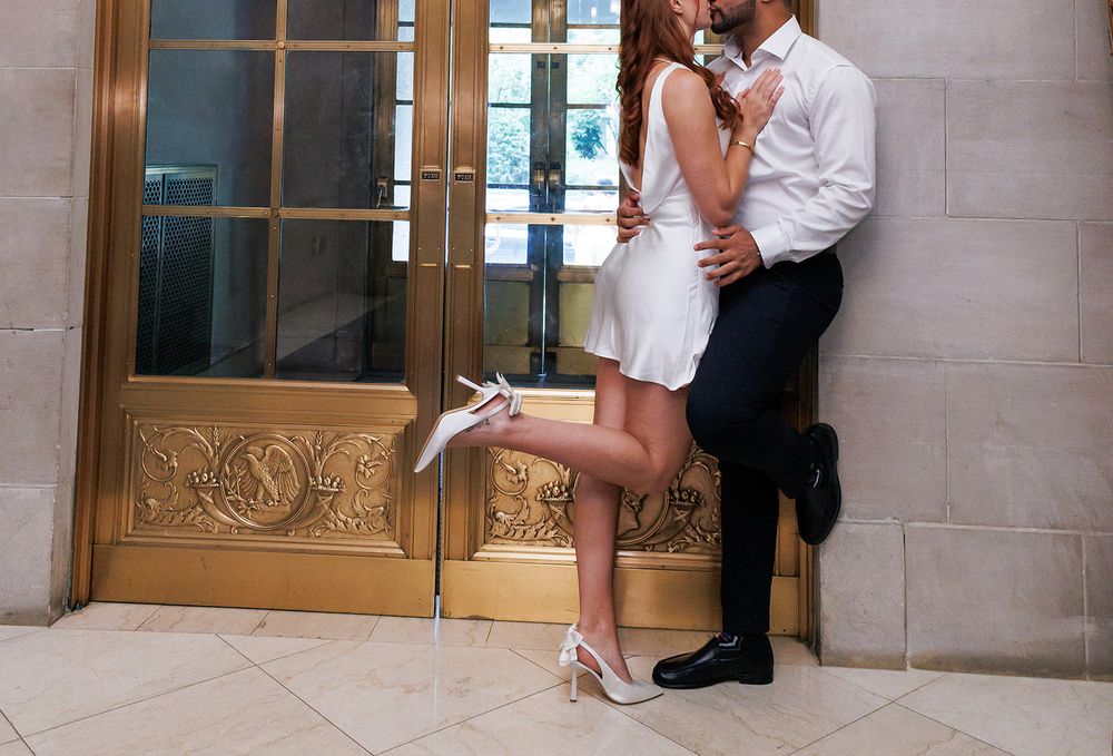 A romantic moment captured by ornate gold doors in a luxury hotel hallway.