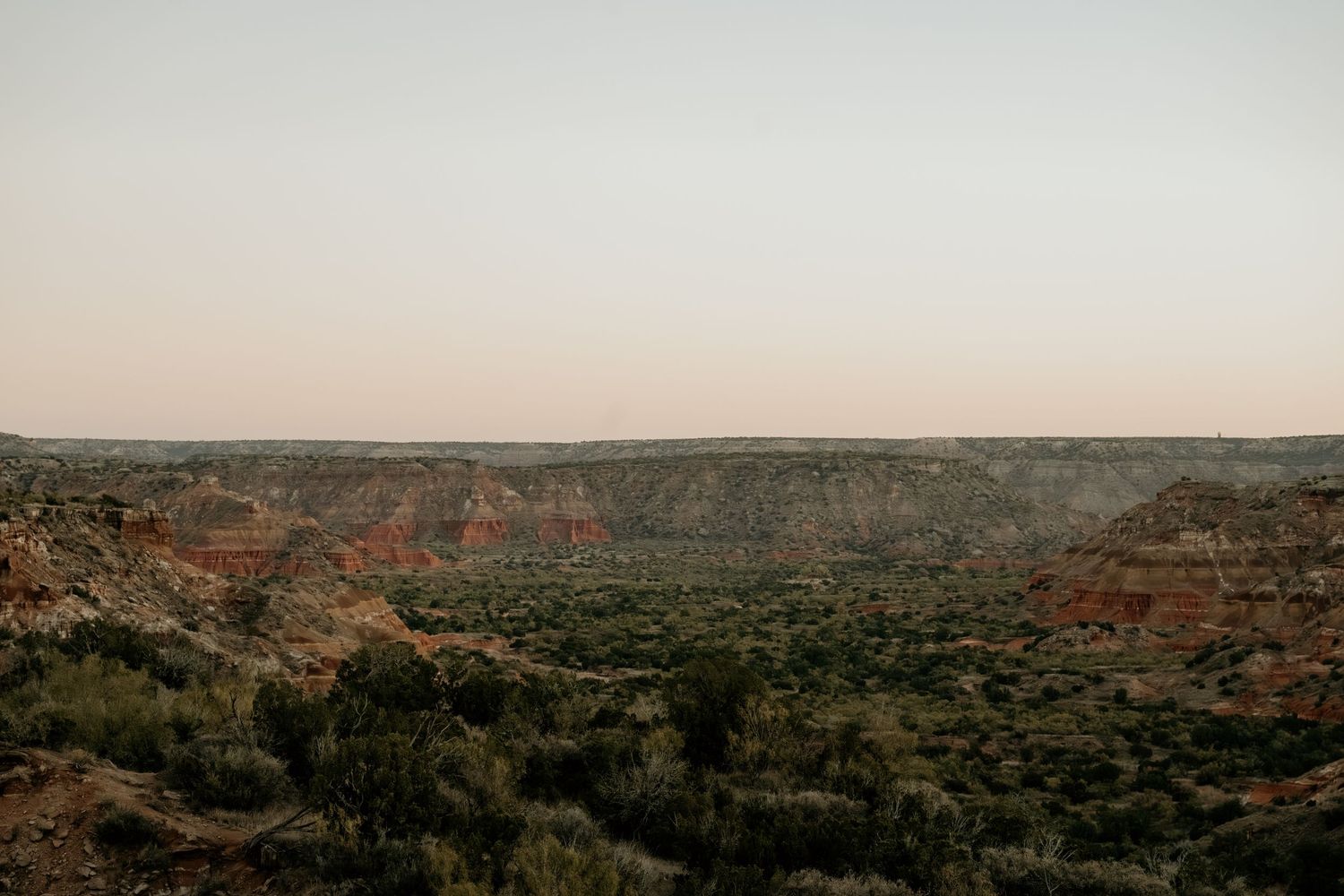 Panoramic desert landscape view with distant rock formations at sunset.