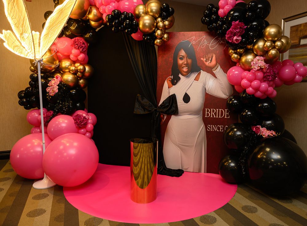 Pink and black balloon arch decorations with gold accents create an elegant party atmosphere.