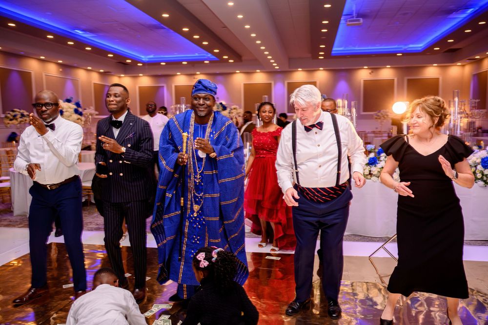 Wedding guests dance together on a ballroom floor illuminated by blue uplighting during an evening reception celebration.