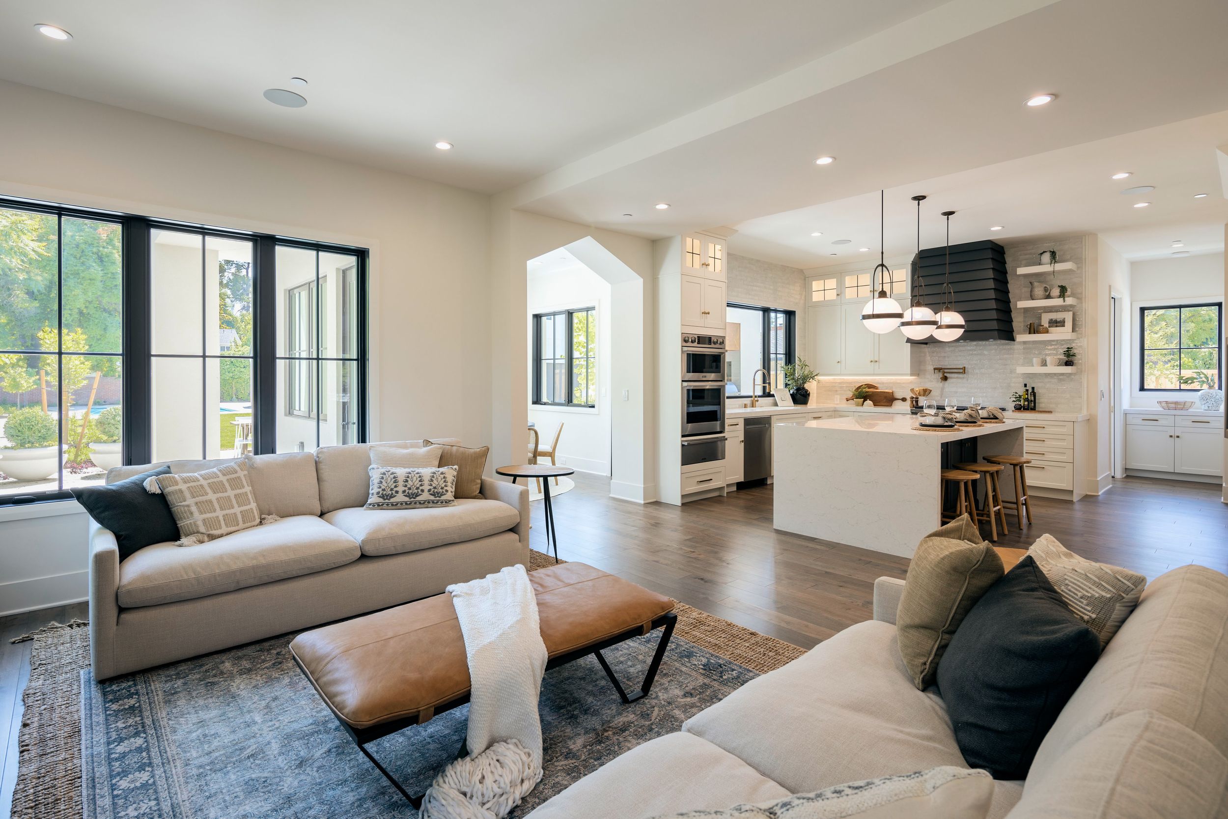 Contemporary living room with panoramic windows showcases neutral decor, plush seating, and seamless open floor plan design.
