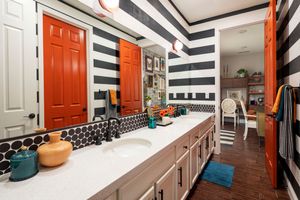Modern mudroom with black and white striped walls, orange doors, and built-in storage benches with turquoise cushions.