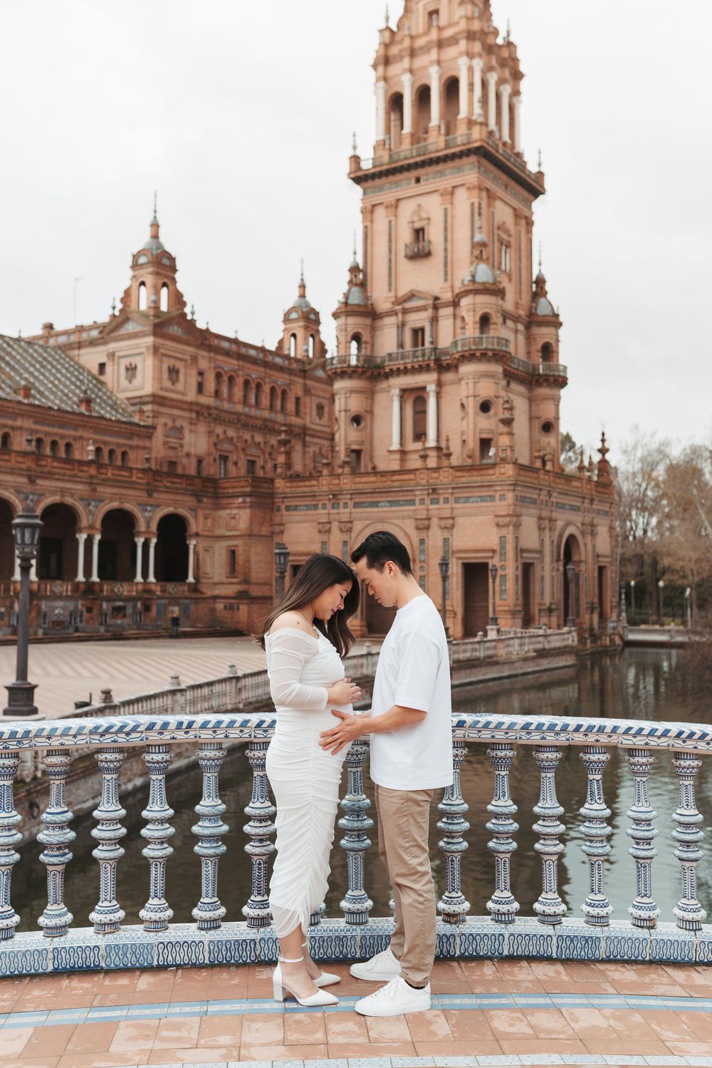 Expecting couple shares intimate moment along decorative balustrade at historic Plaza de España.