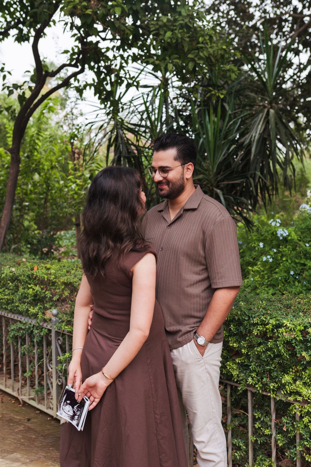 Couple sharing intimate moment in lush garden setting with tropical plants.